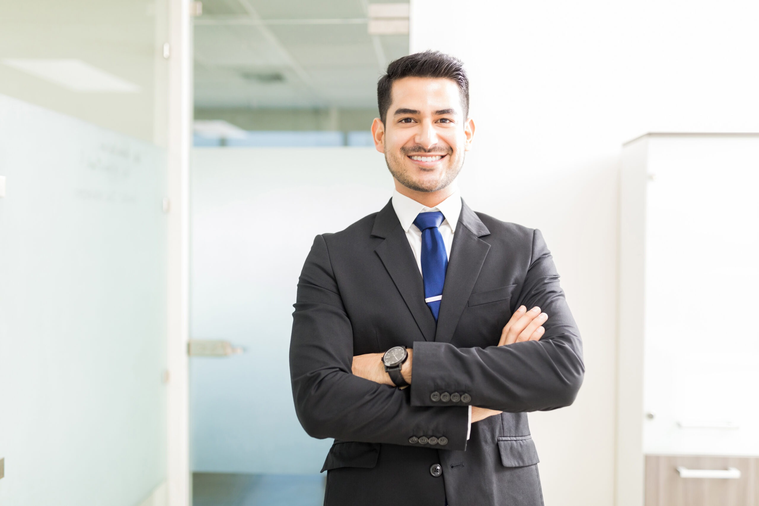 A young divorce lawyer in a suit smiles warmly in his office.