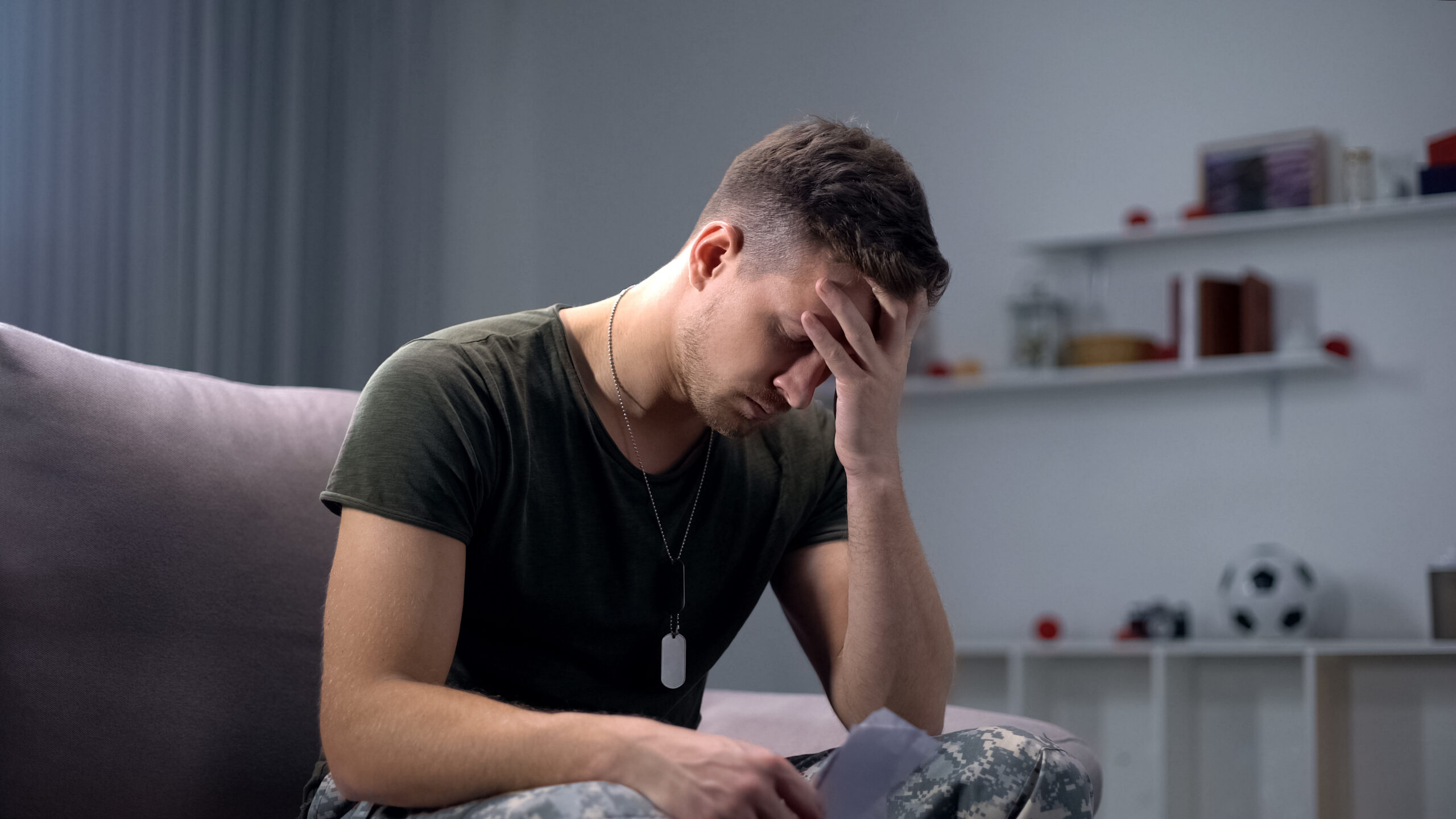Depressed soldier holding photo, suffering from news of impending divorce from spouse while he was away during his service.